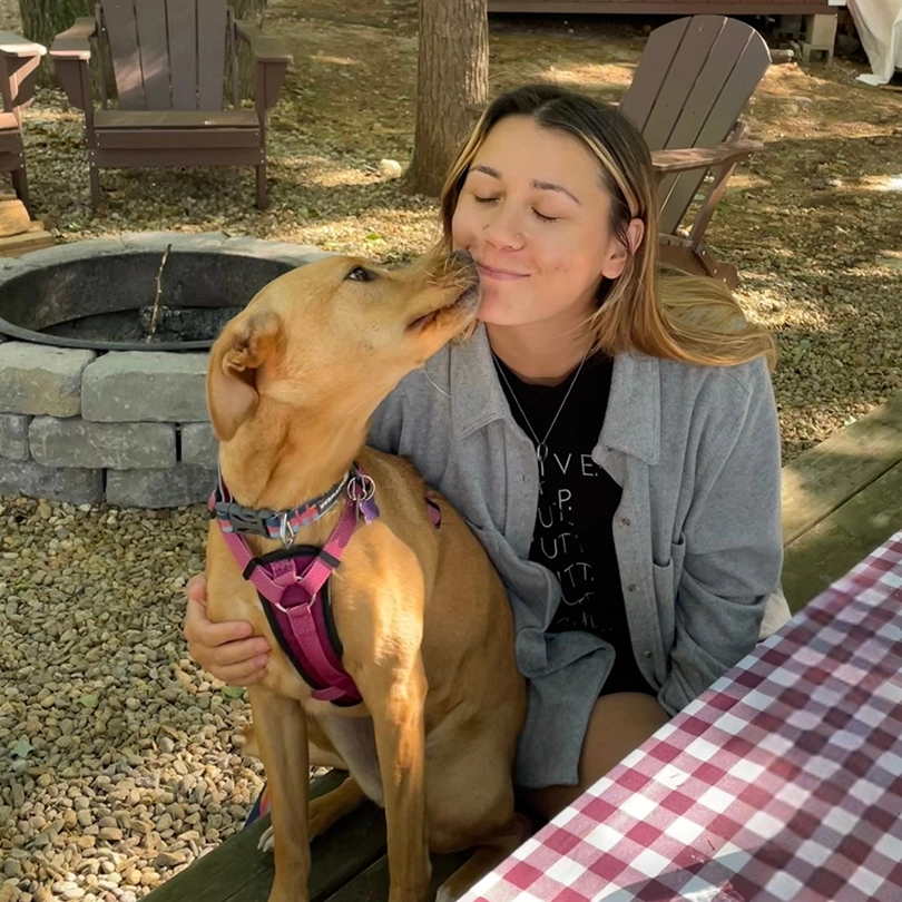 Jess Larsen getting a kiss from her dog at a campground